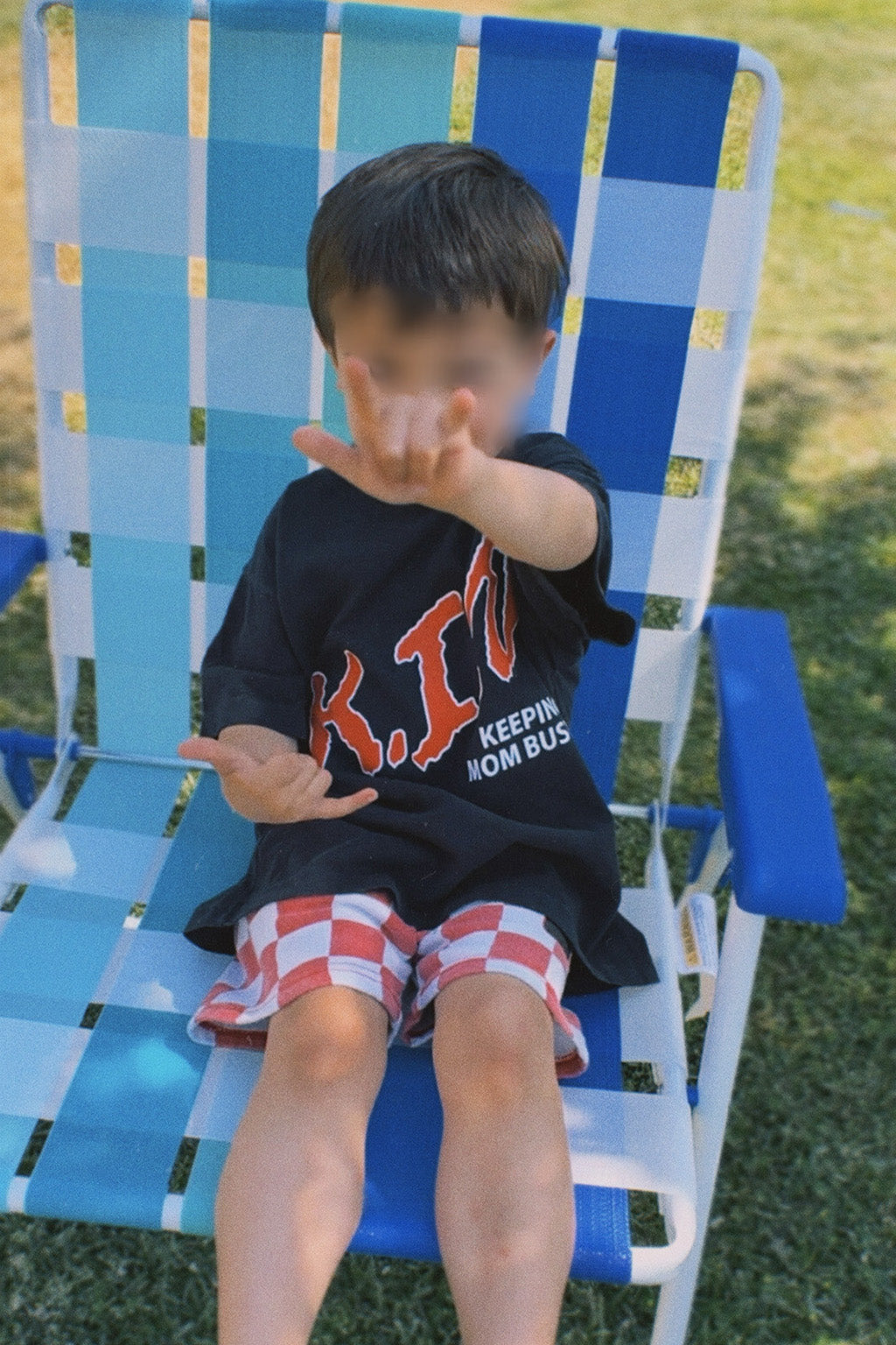 Child sitting on a blue checkered chair outdoors
