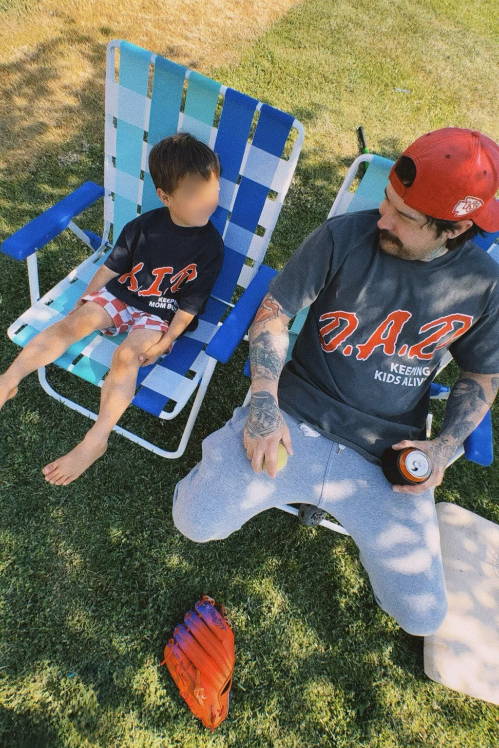 Man and child sitting on lawn chairs outdoors with sports equipment