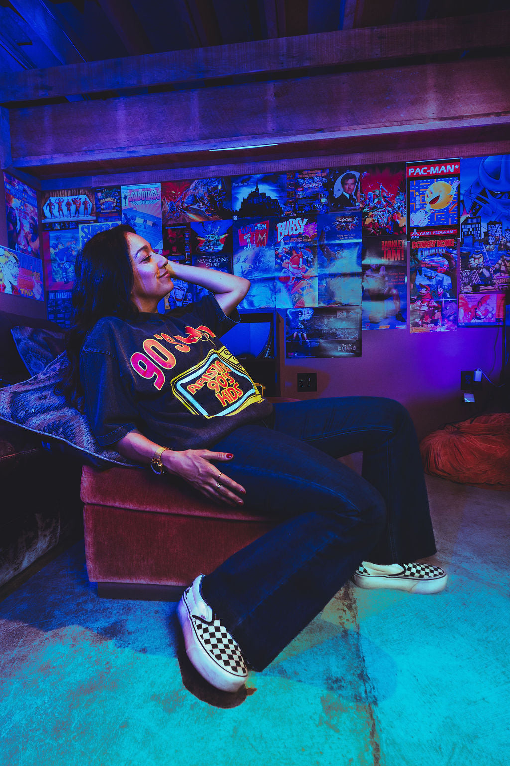 Person sitting in a room with retro gaming posters and neon lights