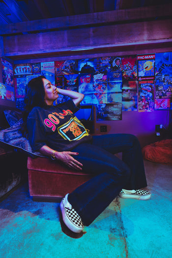 Person sitting in a room with retro gaming posters and neon lights
