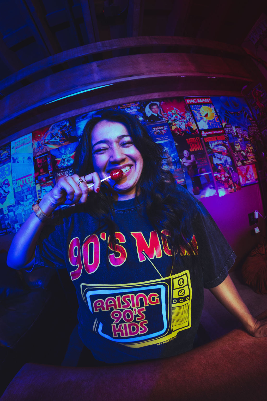 Person wearing a '90s Mom Raising 90s Kids' shirt in a room with retro posters.