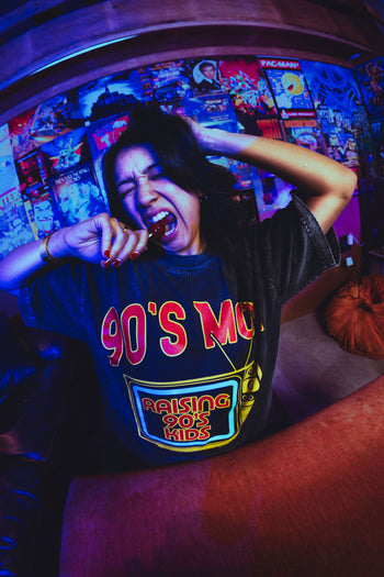 Person wearing a '90s Mom' t-shirt in a room with retro video game posters.